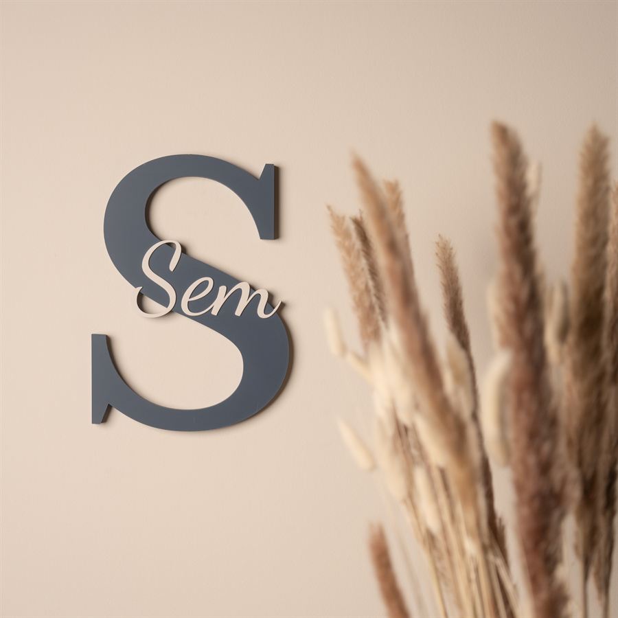 Houten letter S met de naam Sem aan een lichte muur, naast droogbloemen